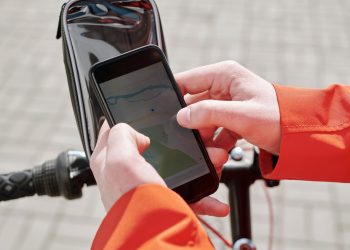 Close-up of cyclist using a smartphone GPS navigation app on a bike mount outdoors.