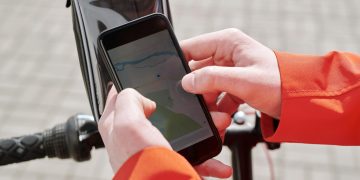 Close-up of cyclist using a smartphone GPS navigation app on a bike mount outdoors.