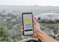Smartphone displaying connectivity app with Los Angeles cityscape in the background.