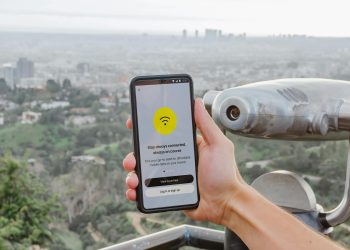 Smartphone displaying connectivity app with Los Angeles cityscape in the background.