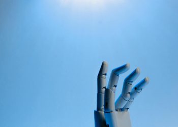Robotic hand with articulated fingers reaching towards the sky on a blue background.