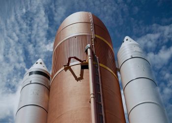 Dramatic view of rocket boosters against a bright blue sky, showcasing aerospace technology.