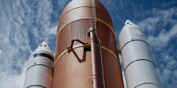 Dramatic view of rocket boosters against a bright blue sky, showcasing aerospace technology.