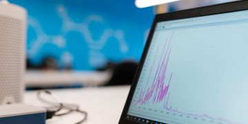 Laptop displaying data analytics graph in a modern office setting, symbolizing growth and technology.