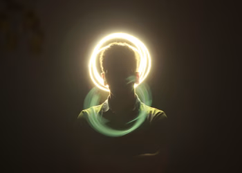Artistic silhouette of a man with a vibrant halo light effect and motion blur on a dark background.