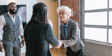 Three entrepreneurs meeting and shaking hands in a modern office setting.