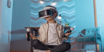 Young boy sitting and playing with VR goggles in a cozy room setting.