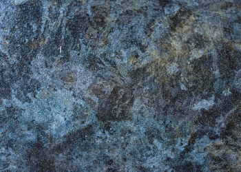 Detailed close-up of a rough, textured stone surface with blue and gray tones.