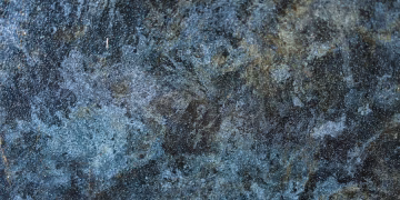 Detailed close-up of a rough, textured stone surface with blue and gray tones.