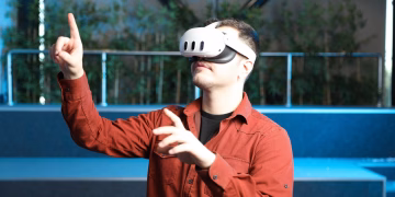 A man wearing a VR headset interacts with augmented reality indoors.