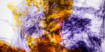 A vivid abstract image of colorful ink swirling through water, creating dynamic patterns and textures.