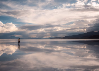 Serene scene of a traveler at Uyuni Salt Flats with stunning reflections and sky.