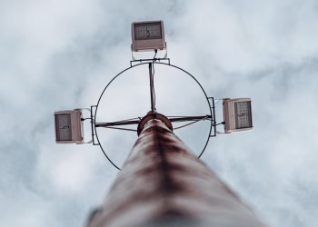 Dramatic low angle shot of a high mast lighting pole against an overcast sky.