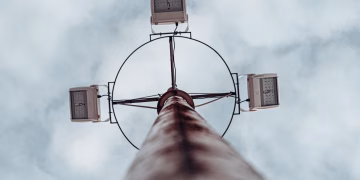 Dramatic low angle shot of a high mast lighting pole against an overcast sky.