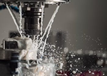 Dynamic close-up of CNC machine with coolant splashing during metalwork operation.