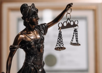 Close-up of a bronze Lady Justice statue holding scales in an office environment.