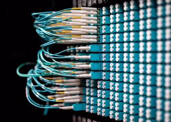 Server with electronic switches and connectors with yellow and green wires plugged in plastic device in operating room on black background