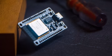 Microcontroller chip with screwdriver on dark surface, ideal for tech and innovation themes.
