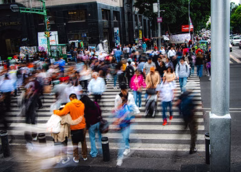 A bustling city street with a crowd of pedestrians crossing a zebra crossing, showcasing urban life.