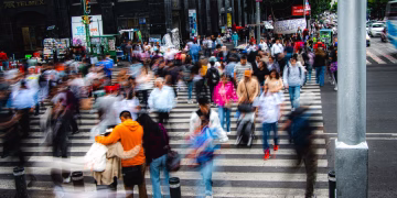 A bustling city street with a crowd of pedestrians crossing a zebra crossing, showcasing urban life.