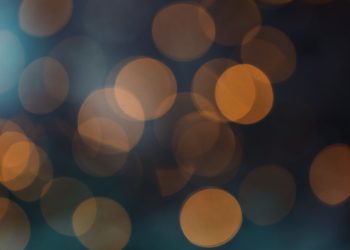 Abstract bokeh background with warm orange circles on a dark backdrop.