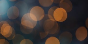 Abstract bokeh background with warm orange circles on a dark backdrop.