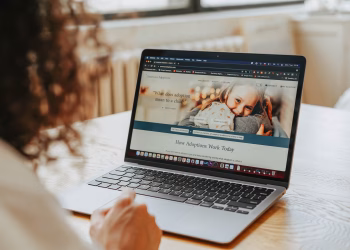 A woman researching adoption information on a laptop indoors.