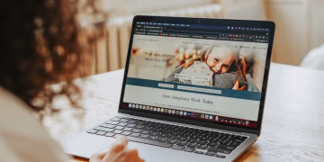 A woman researching adoption information on a laptop indoors.