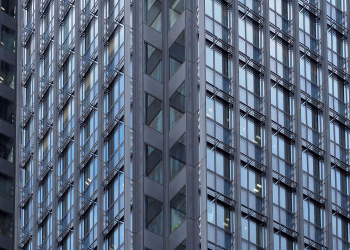 Close-up of a modern skyscraper's glass and steel facade in downtown Tokyo, Japan.