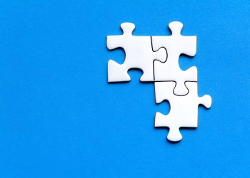 White jigsaw puzzle pieces on a vivid blue background from a top view, perfect for creative concepts.