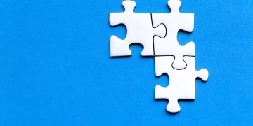 White jigsaw puzzle pieces on a vivid blue background from a top view, perfect for creative concepts.