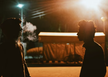 Silhouette of two men talking under streetlights in Taxila, Pakistan at night.