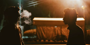 Silhouette of two men talking under streetlights in Taxila, Pakistan at night.