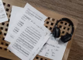 Music sheets and headphones arranged on a wooden surface, perfect for musical inspiration.