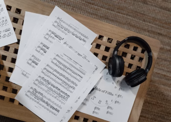 Music sheets and headphones arranged on a wooden surface, perfect for musical inspiration.