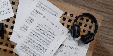 Music sheets and headphones arranged on a wooden surface, perfect for musical inspiration.
