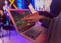 A vibrant scene with hands pointing at a computer with code on display, suggesting tech focus.