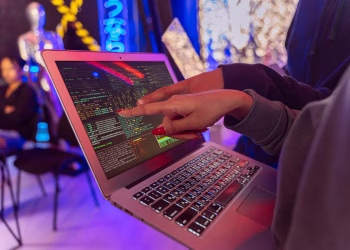 A vibrant scene with hands pointing at a computer with code on display, suggesting tech focus.