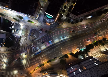A vibrant aerial view of illuminated streets and traffic in Busan at night.