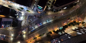 A vibrant aerial view of illuminated streets and traffic in Busan at night.