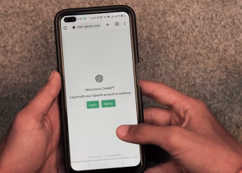 Close-up of hands using smartphone with ChatGPT app open on screen.