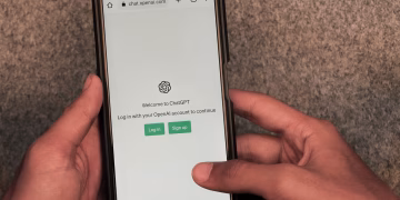 Close-up of hands using smartphone with ChatGPT app open on screen.