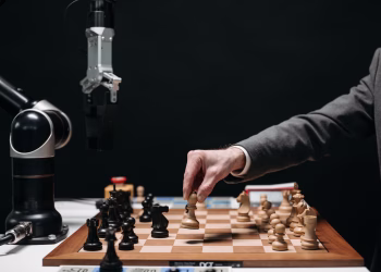 A robotic arm plays chess against a human, symbolizing AI innovation and strategy.