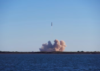 A rocket launch with smoke trails over South Padre Island, viewed across the ocean.