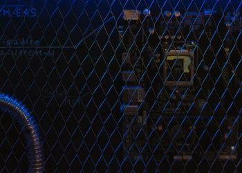 Artistic view of a circuit board through metal mesh with blue lighting.