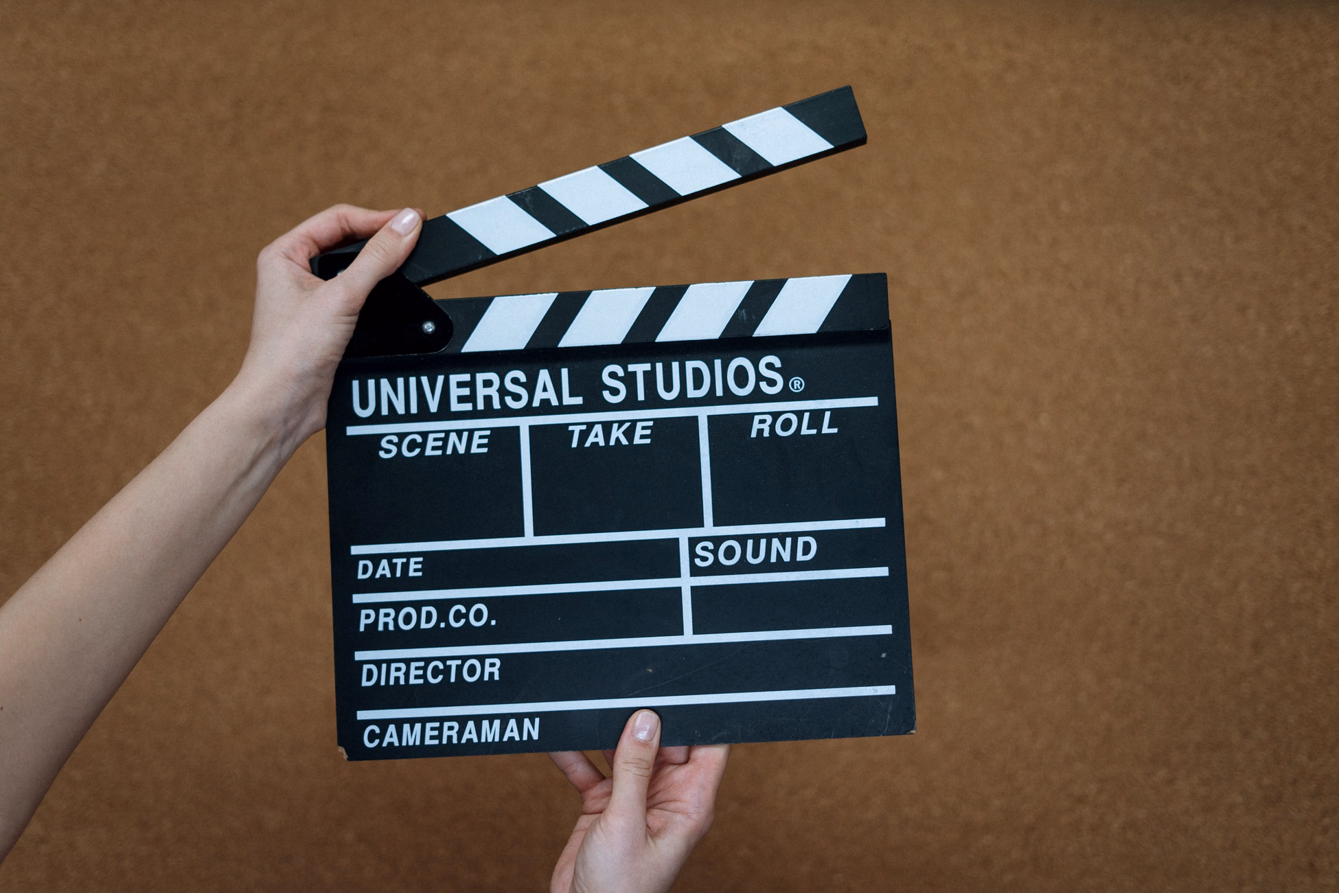 Close-up of hands holding a Universal Studios clapboard on a cork backdrop, ready for filming.