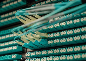 Detailed view of fiber optic cables connected to a server rack, showcasing modern technology.