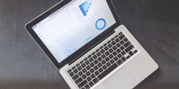 Overhead view of a laptop showing data visualizations and charts on its screen.