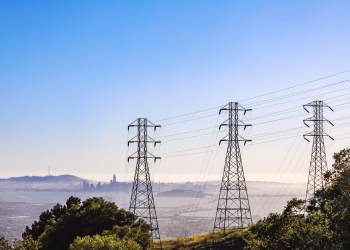 Electrical pylons with city skyline and bay view on a clear day.