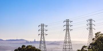 Electrical pylons with city skyline and bay view on a clear day.